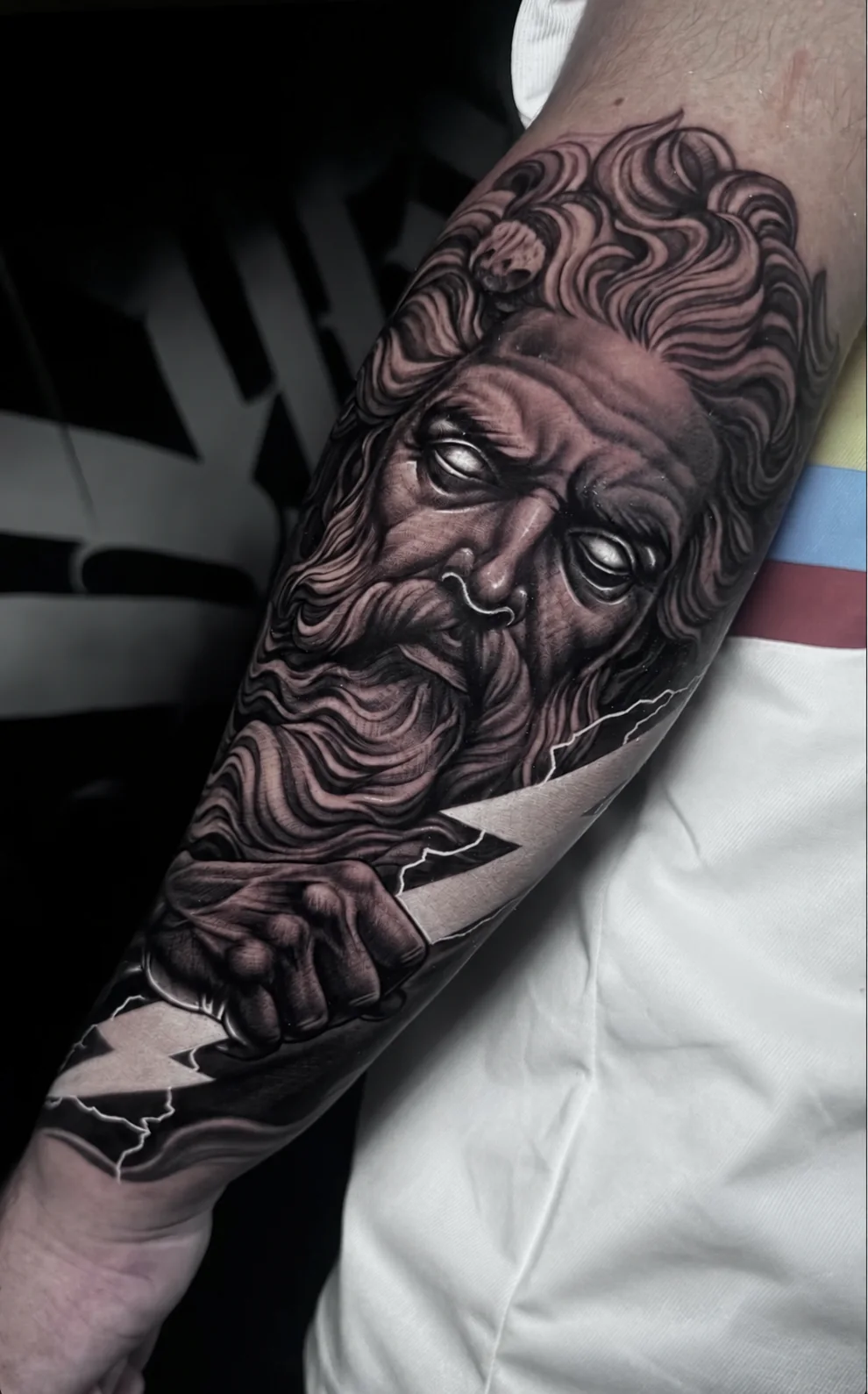 Tatuaje realista black and grey de un dios griego en el antebrazo, en Black Rituals Tattoo Málaga